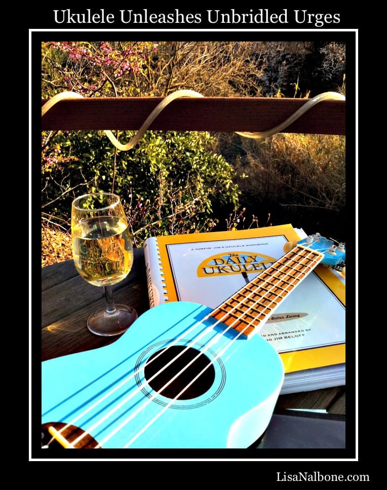 Blue ukulele, glass of wine and daily ukulele music book on deck. Ukulele Unleashes Unbridled Urges by Lisa Nalbone